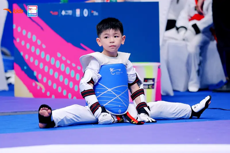 Young fighter in a WayChamp chest protector sitting on the mat